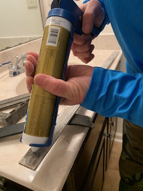 applying adhesive to frame a wall mirror
