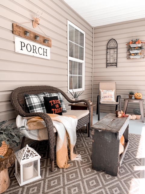 A screened in back porch decorated for Halloween and fall