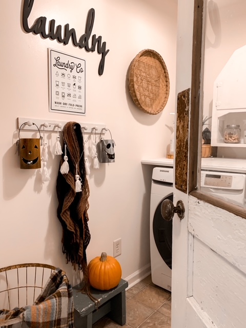 a farmhouse style laundry room with fall decorations such as cute Halloween lanterns, a yarn ghost garland, and a faux pumpkin