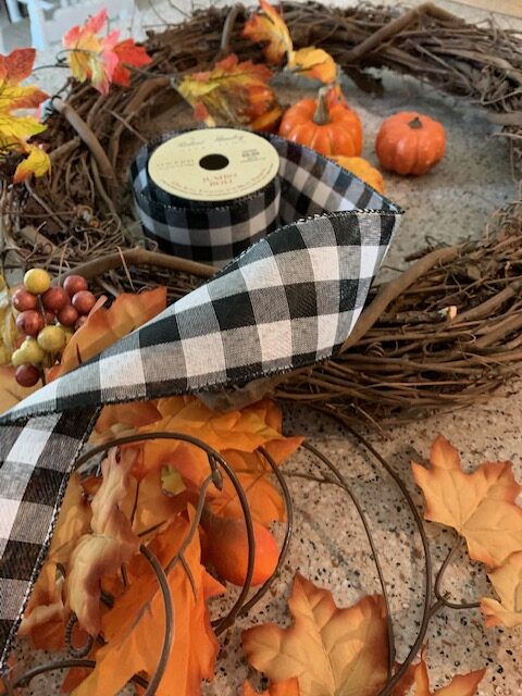 fall wreath inspiration with orange leaves, berries, black and white ribbon, and a grape vine wreath for more texture