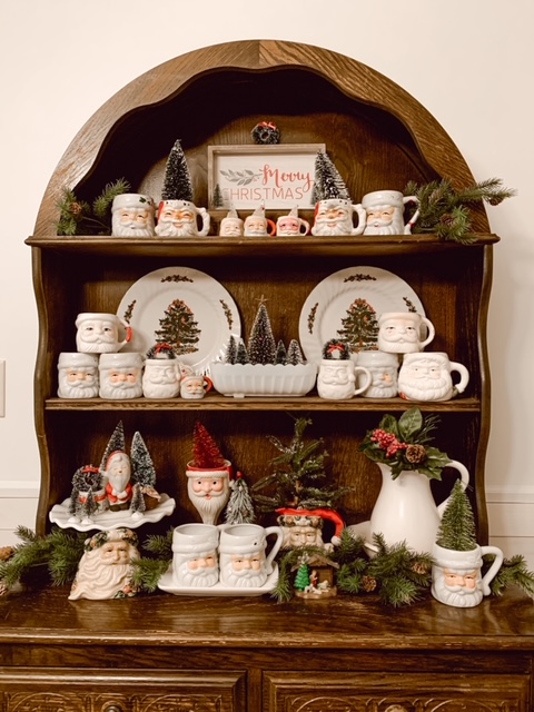 A collection of vintage Santa mugs on a dining room hutch