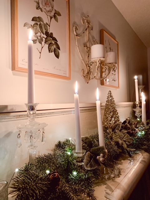 A romantic winter mantle decorated with candles, winter greens, and twinkle lights