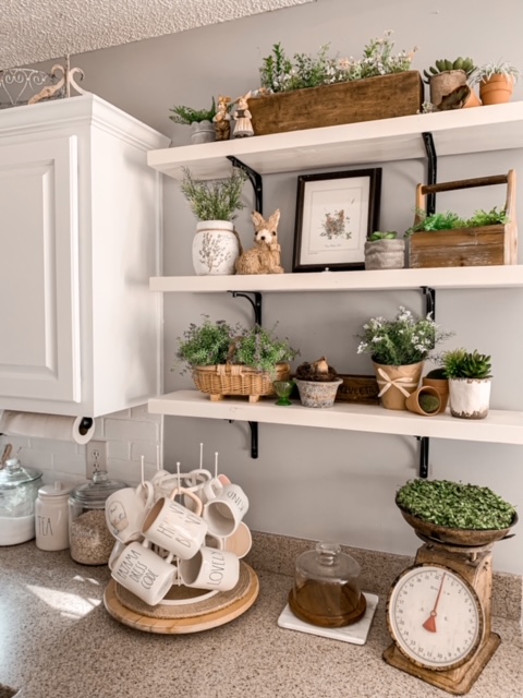 kitchen open shelves are styled for spring with lots of greenery, bunnies, and bird nests