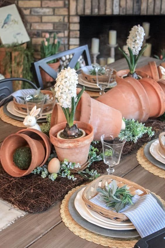 a garden theme spring centerpiece using small clay pots, a ceramic bunny, and flowers