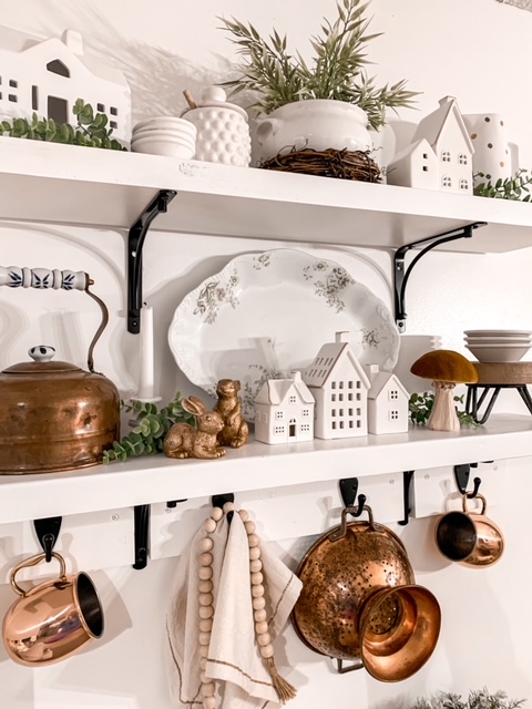 kitchen open shelves are styled for early spring with copper pieces, bunny figurines, and white ironstone
