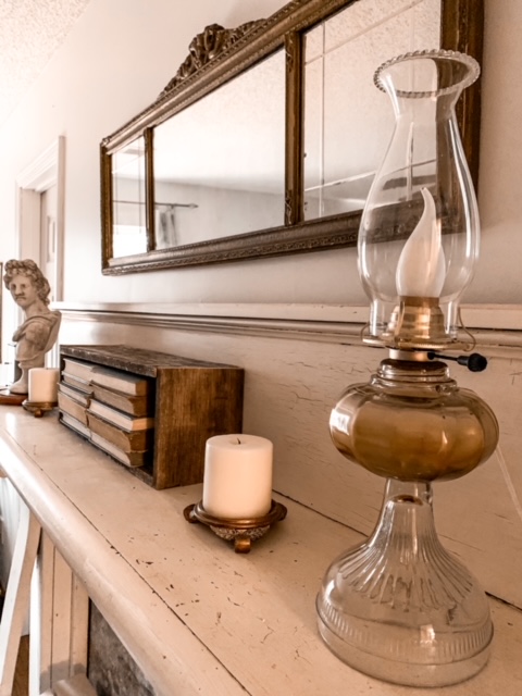 an antique mantel is styled with an antique oil lamp that was converted to electric