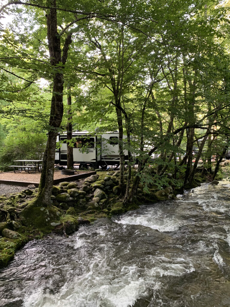 RV camper next to a mountain stream