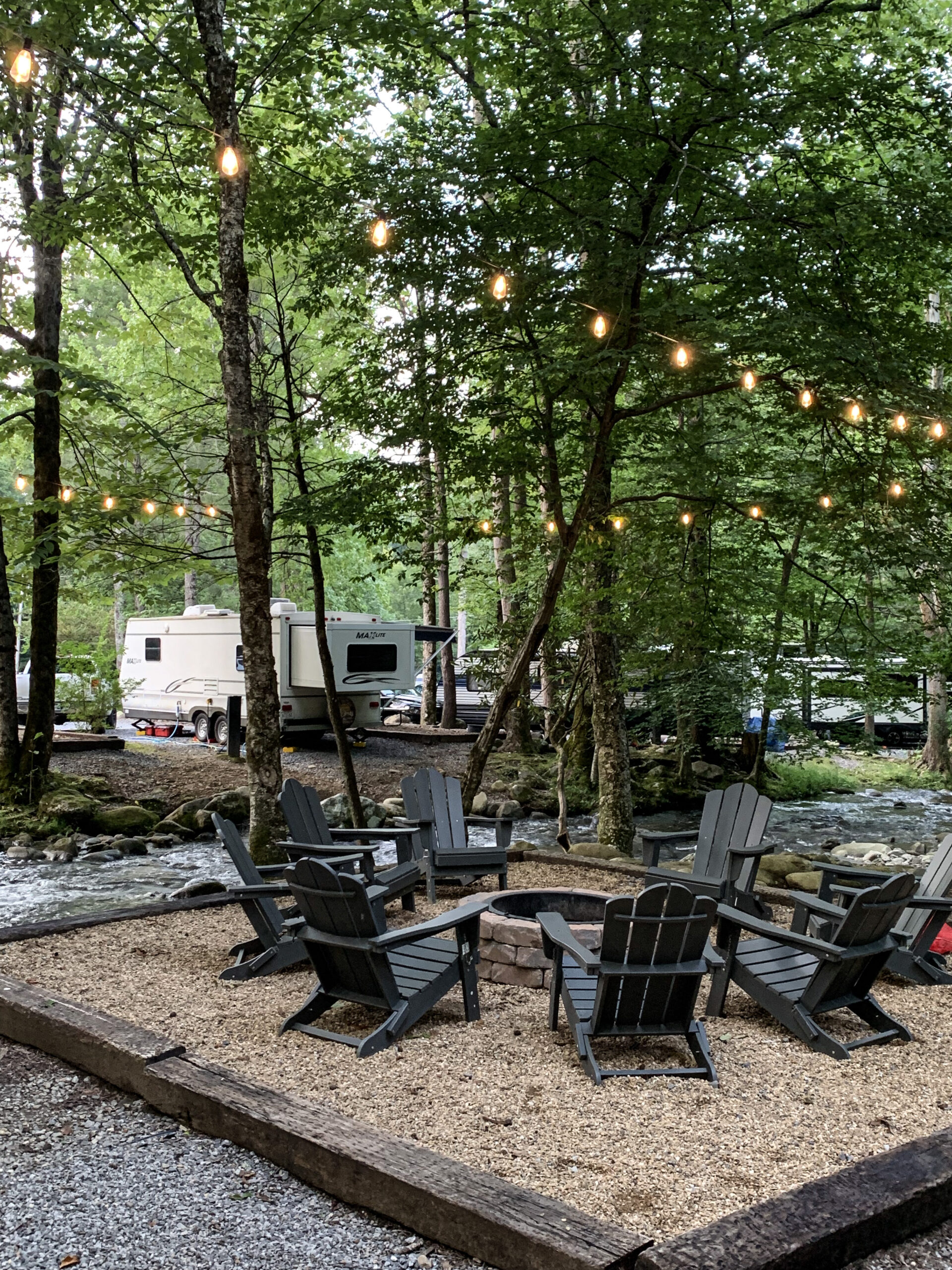 an rv near the creek and community fire pit area of a campground